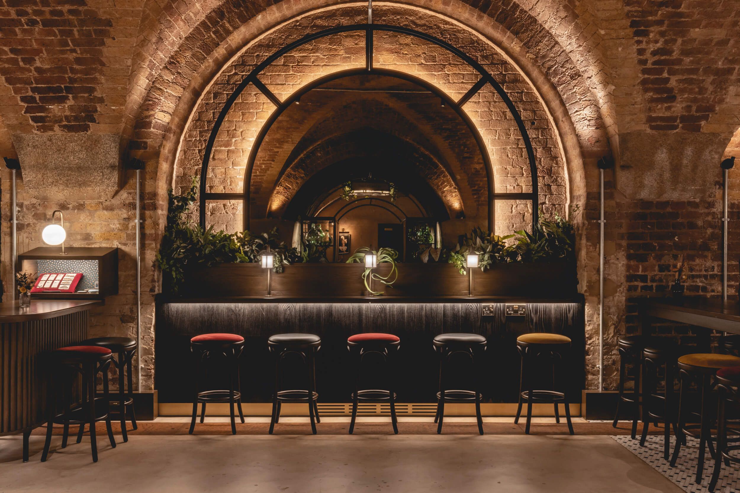 Row of stools facing a mirror in a bar.